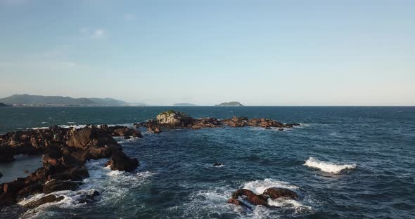 Aerial footage of the the beautifu rocks and sunny beach of Armação in Florianópolis, Brazil. alt