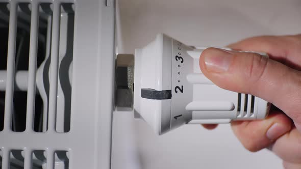 Man Sets the Temperature of the Radiator in the Room, Energy Saving Concept alt