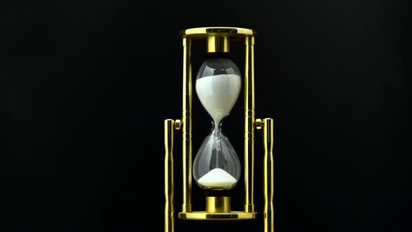 Time Passing While Sand Falls Through Hourglass. Black Background alt