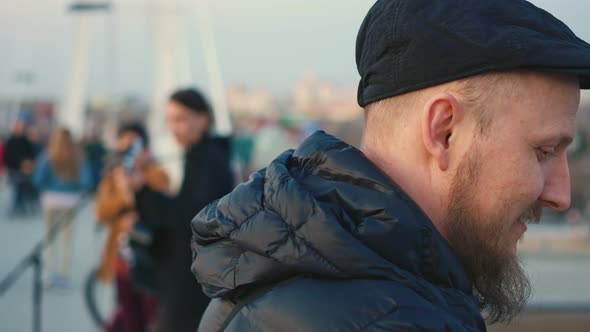 Portrait of a Blueeyed Bearded Man in a Cap Listening to Music alt