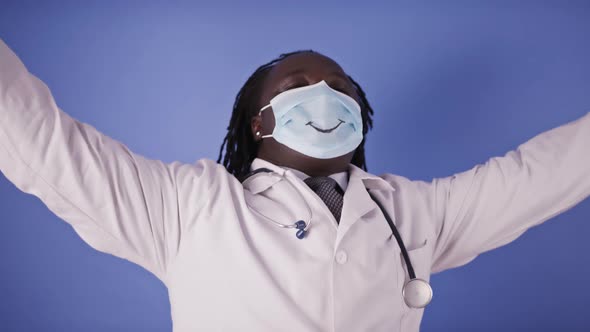 Dancing African Doctor in Face Mask with Smile on Isolated on Blue Studio Background alt