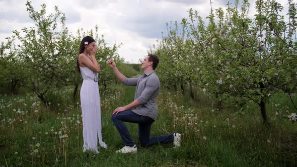 Man Making Marriage Proposal To Woman in Orchard alt