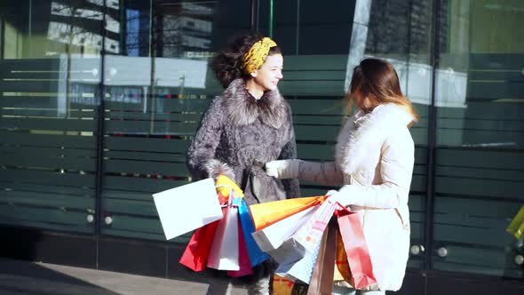 Two Cheerful Girlfriends Talking Near the Shop Window