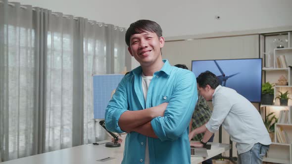 Smiling Asian Man Engineer Crossing His Arms To Camera While His Colleagues Are Discussing Working alt