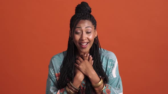 A happy surprised african american woman doing heartwarming gesture alt