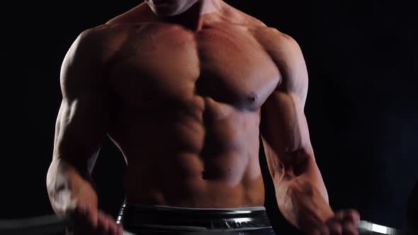 Weightlifter Lifts a Barbell To Training Biceps. Black Background alt