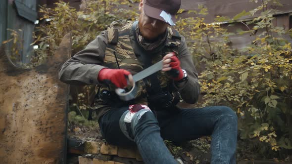 Man Bandaging Wounded Leg with Duct Tape Hiding From Zombie  alt