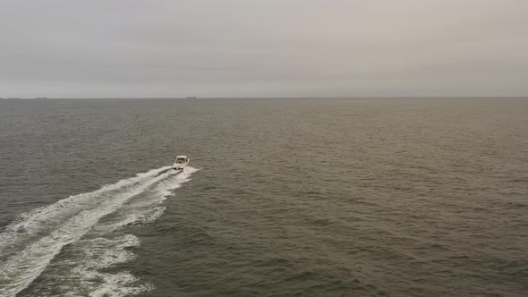 An aerial view of a small, white fishing boat speeding in the deep Atlantic Ocean out by Long Island alt