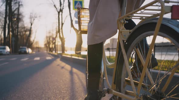 Woman with Long Scythe in Scarf Rides Yellow Bicycle on Road alt