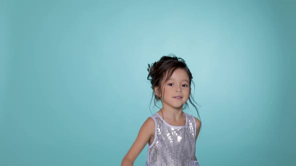 Beautiful Little Child Girl in Silver Dress Dancing on Blue Background.
