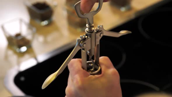 A Mans Hands Twists of a Bottle Opener on a Wine Bottle alt
