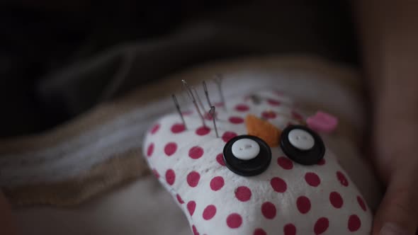 Close-up view of female hands inserting pins into pin cushion in shape of owl. Handmade concept.