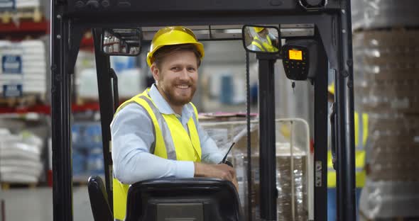 Portrait Young Male Warehouse Worker Sitting in Forklift Truck and Smiling at Camera alt