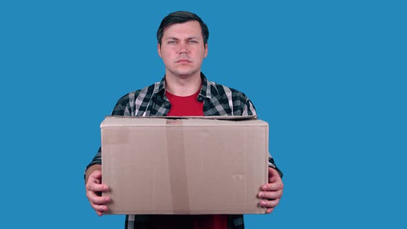Delivery man holding a parcel box - isolated on blue background.