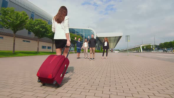 The Guy Makes a Marriage Proposal Near the Airport Terminal. The Bride with Luggage in Her Hands alt