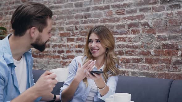 Adorable Smiling Amorated Man and Woman Sitting in Hotel Lobby and Having Fun Together alt