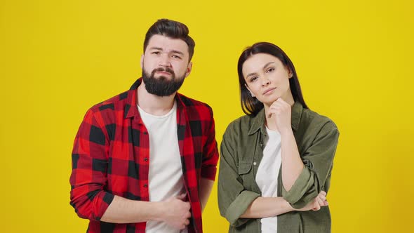 Caucasian Young Stylish Couple Looking at Camera on Yellow Background and Suddenly Guess Reaction of alt