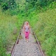 Female walking on empty train railway surrounded by tropical grass and trees - VideoHive Item for Sale