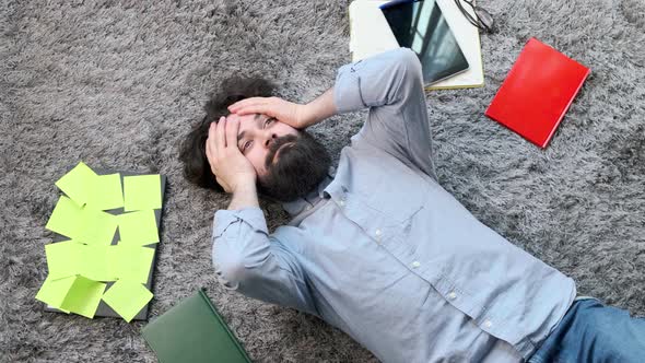 Young Man Surrounded By Computer and Documents Very Tired and Exhausted alt