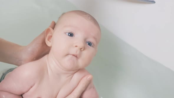 Mom and son are engaged in infant swimming in the home bathroom