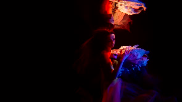 Pretty Young Woman and Her Tamed Dragon are Floating in Calm Dark Depth of Ocean Underwater alt