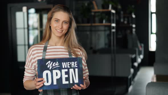 Portrait of Attractive Blond Waitress Holding Open Sign in New Cafe Smiling alt