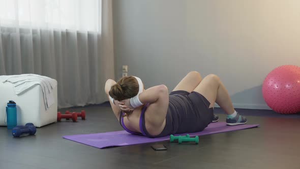 Chubby Lady Gathering All Her Strength and Doing Crunches to Shape Her Body alt