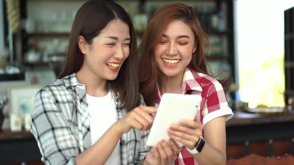 two happy woman using digital tablet in a café