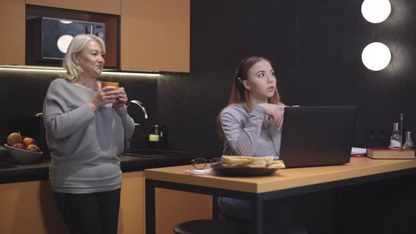 Adolescent Girl in Headphones Talking in Video Chat on Laptop and Asking Senior Mother To Leave the alt