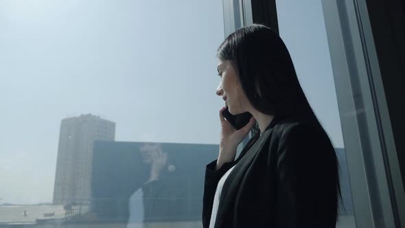 Young Business Woman in a Modern Office Skyscraper Near the Panoramic Window Enjoying the View and