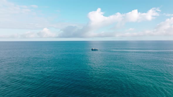 Aerial Drone Tracking Video of Touristic Boat Cruising in Blue Open Ocean Sea alt