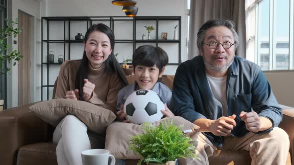 Asian family watching football sports games on TV alt