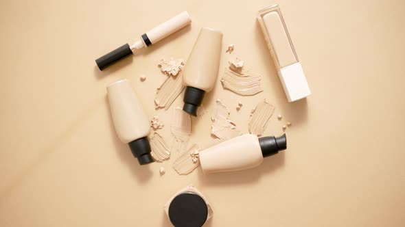 Bottles of Makeup Foundation and Samples on Beige Background