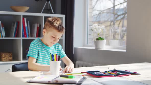 Boy is Doing  Homework at the Table. Cute Child is Learning at Home. alt