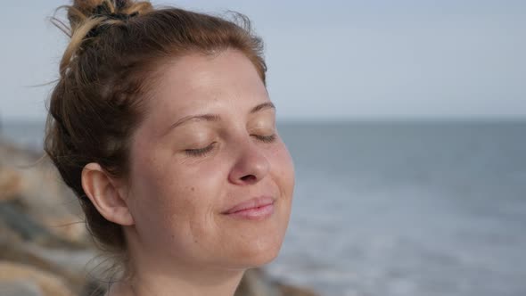 Young beautiful female on ocean coast relaxing Caucasian blonde  woman enjoying beach sun by meditat