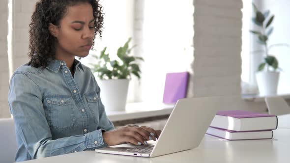 Pensive Creative African Girl Thinking and Working on Laptop alt