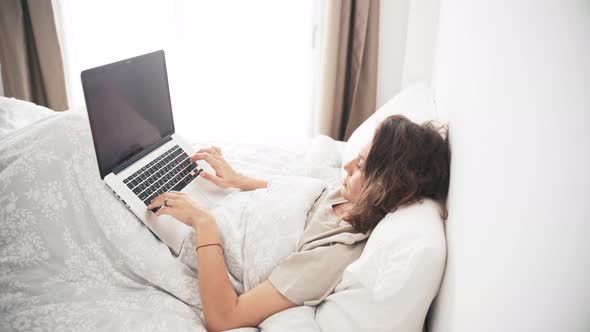 A Young Woman Remote Employee Working at Home Using Her Laptop alt