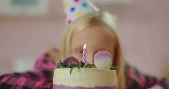 Close Up of Little Girl Blowing Out Candle on Birthday Cake in Slow Motion. Schoolgirl Celebrates alt
