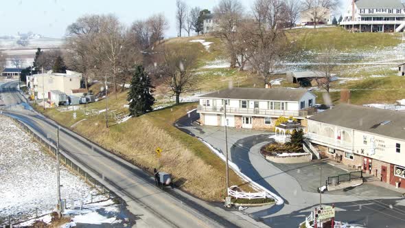 AERIAL Horse-Drawn Carriage Trotting Into Township During Snowfall alt