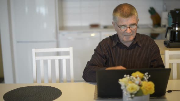Stressed Senior Man Using Laptop and Giving Thumbs Down at Home alt