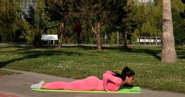 Attractive fit black woman stretching in park, female fitness yoga routine.