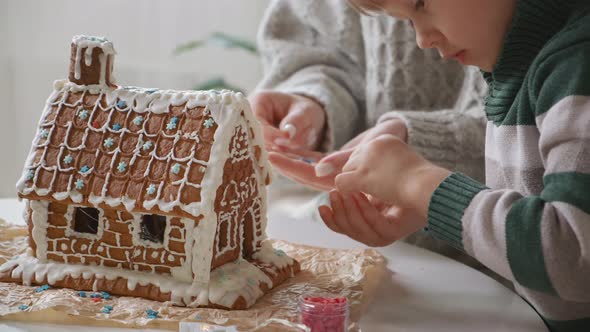 Little Boy with Mother Decorating Christmas Gingerbread House Together Family Activities and alt