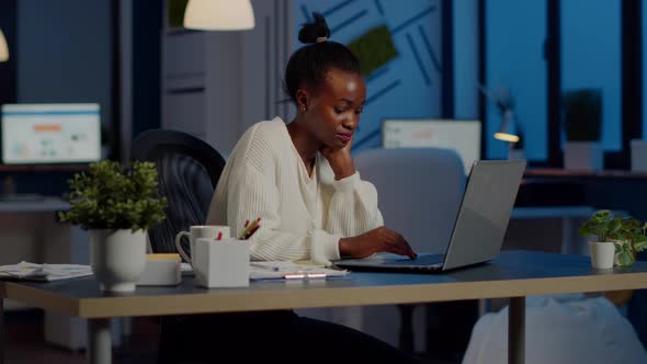 Overworked African Manager Woman Massaging Head While Sitting at Workplace alt
