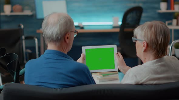 Aged Couple with Chronic Disability Using Green Screen on Digital Tablet alt