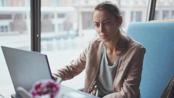 Businesswoman Dressed Casual Sitting in Cafe and Using Laptop. alt
