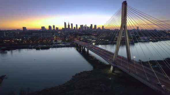Bridge and city of Warsaw illuminated at dusk in cinematic aerial view alt