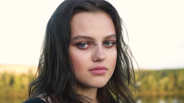 Portrait of a Gorgeous Dark Haired Teenage Girl with Piercings Looking at Camera  alt