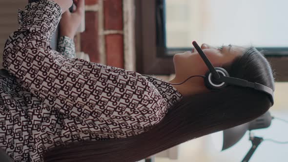 Vertical Video Woman Consultant Using Headphones to Chat on Phone Call alt