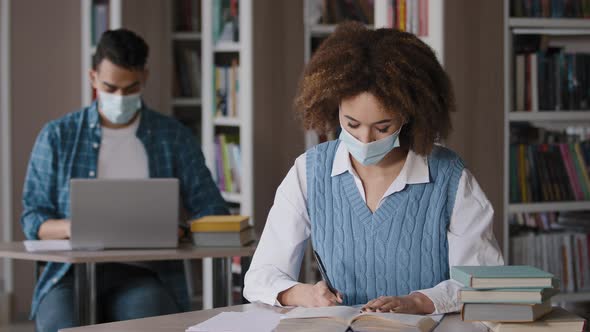 Two Students in Protective Mask Sitting in Classroom at University Library Doing Homework Exam alt