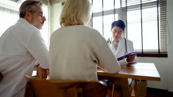 Behind of elderly couple meeting with doctor to get explain result of annual check up report alt